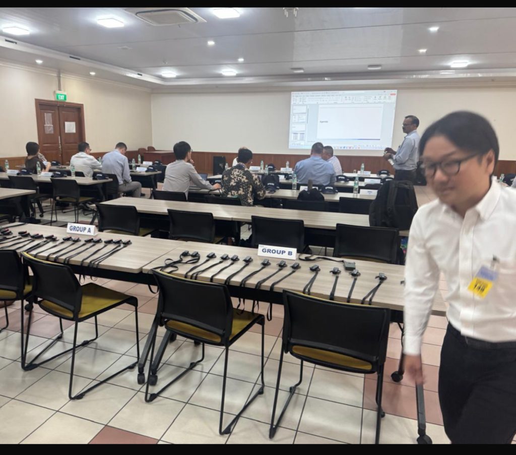 Peserta konferensi mendengarkan penerjemah simultan melalui receiver dan headset SIS Obeqa